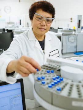A Torrent Laboratory chemist conducts stands in front of machinery to test for dioxin compounds.