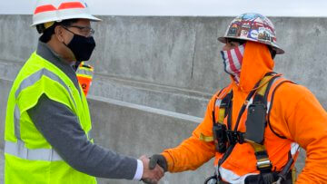 On the deck of a concrete structure, USDOT FRA Deputy Administrator Amit Bose shakes the hand of Adrian Pacheco, a carpenter helping build the nation's first high-speed rail system.