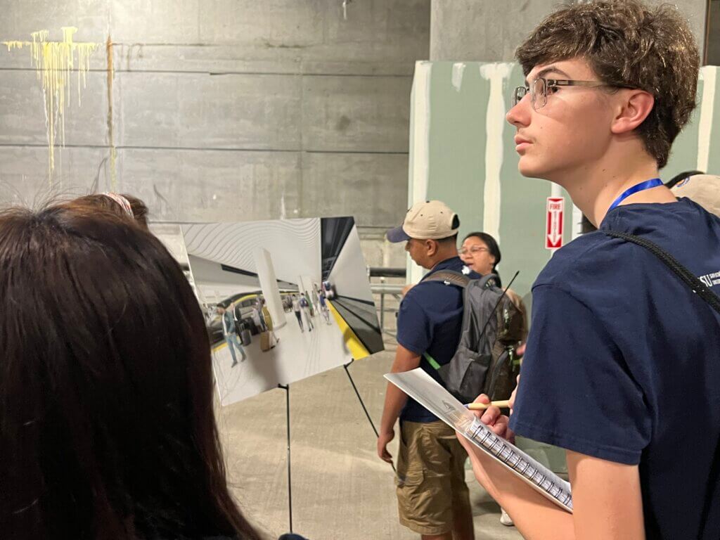 High-school student looking up with some informative pop-up posters to his right.