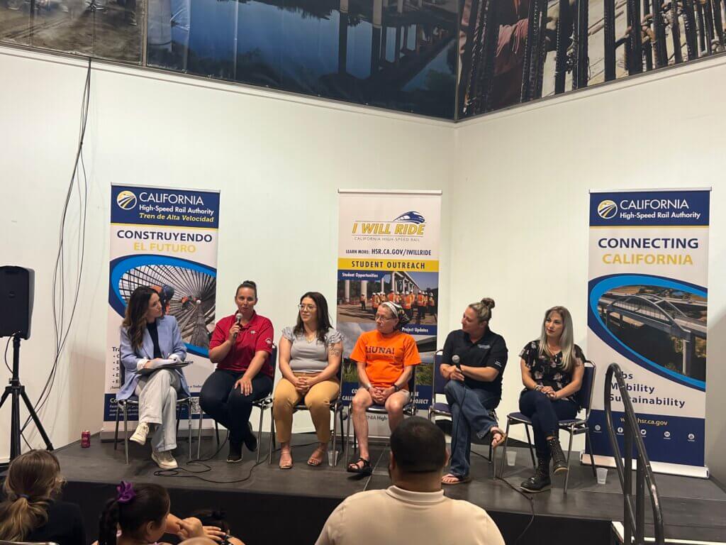 Six women sitting on a stage having a panel discussion. 